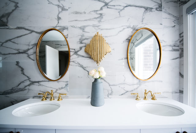 Bathroom with marble effect tiles and oval mirrrors with gold trim